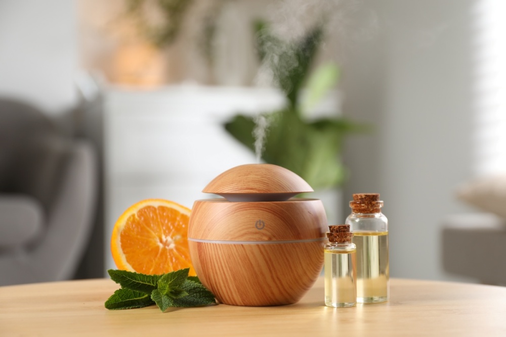 Difuzor aromaterapie si ulei esential de portocala langa jumatate de portocala